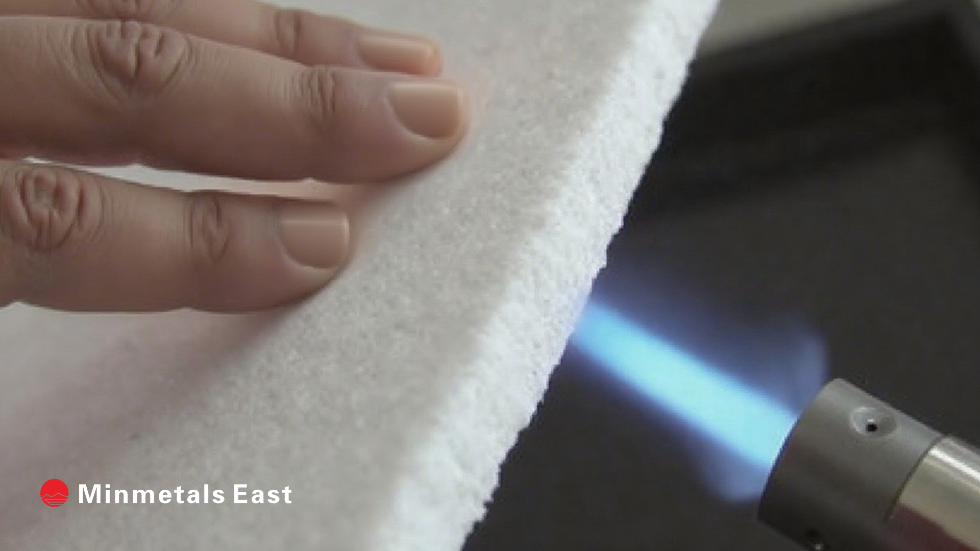Aerogel felt undergoing a thermal conductivity test, showing a white material between two plates with sensors, with 'Minmetals East' logo.